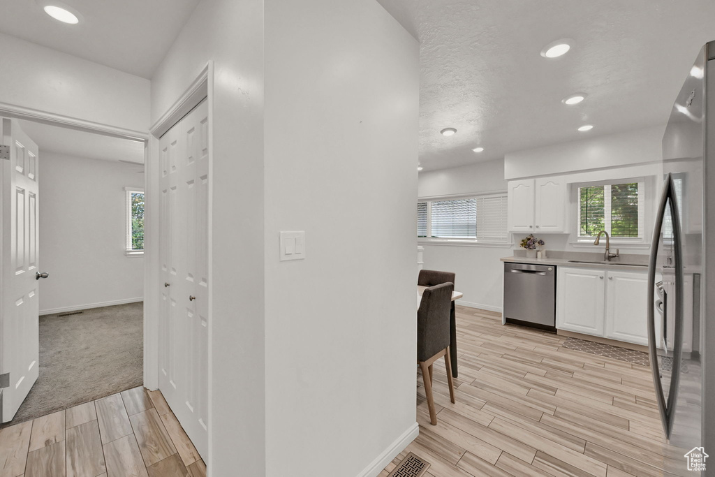 Interior space featuring light hardwood / wood-style flooring, stainless steel appliances, and white cabinetry