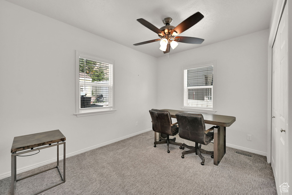 Carpeted home office featuring ceiling fan