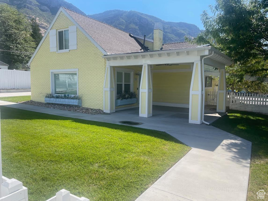 Back of property with a mountain view and a lawn