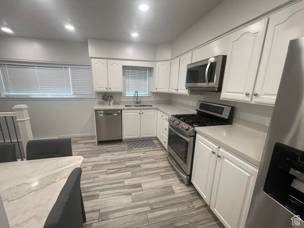 Kitchen featuring white cabinetry, stainless steel appliances, sink, and light hardwood / wood-style floors