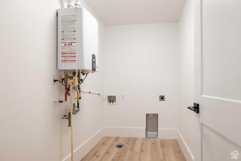 Clothes washing area featuring light wood-type flooring, hookup for a washing machine, hookup for an electric dryer, and tankless water heater