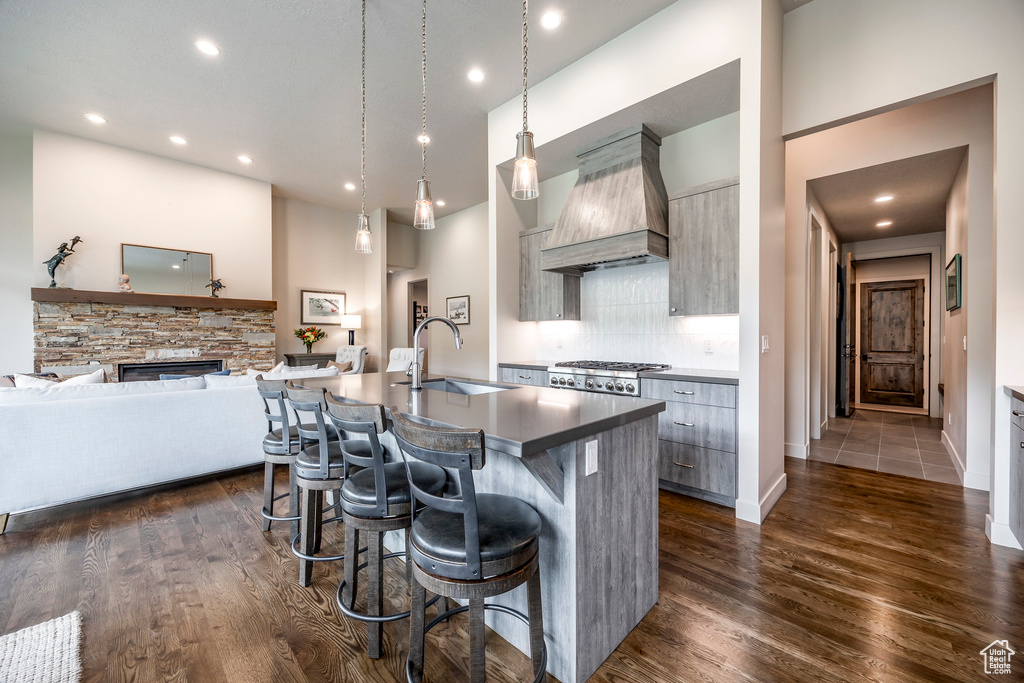 Kitchen with a sink, custom range hood, a breakfast bar area, a center island with sink, and modern cabinets