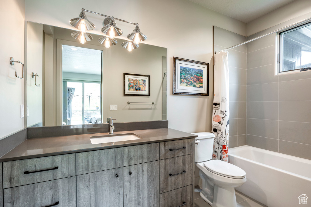 Bathroom featuring toilet, shower / bath combo with shower curtain, and vanity