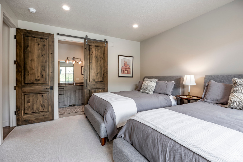 Bedroom featuring a barn door, recessed lighting, and ensuite bathroom