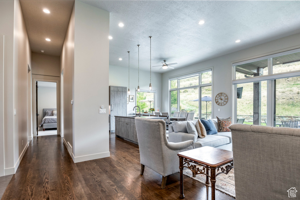 Living area with a ceiling fan, dark wood-style floors, recessed lighting, a textured ceiling, and baseboards