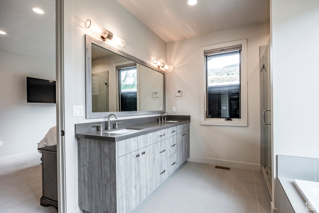Bathroom with double vanity, baseboards, a shower with door, recessed lighting, and a bath