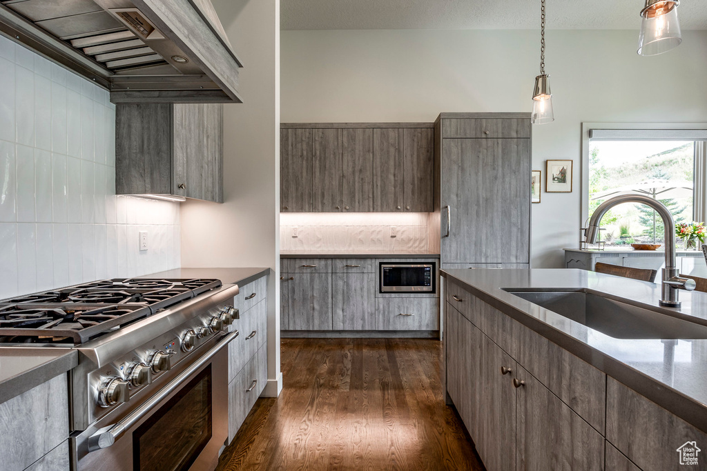 Kitchen featuring appliances with stainless steel finishes, a sink, custom exhaust hood, and tasteful backsplash