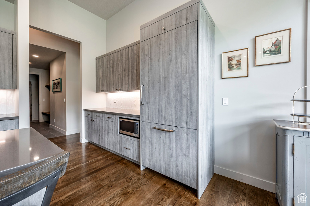 Kitchen with stainless steel microwave, baseboards, dark wood-type flooring, and modern cabinets