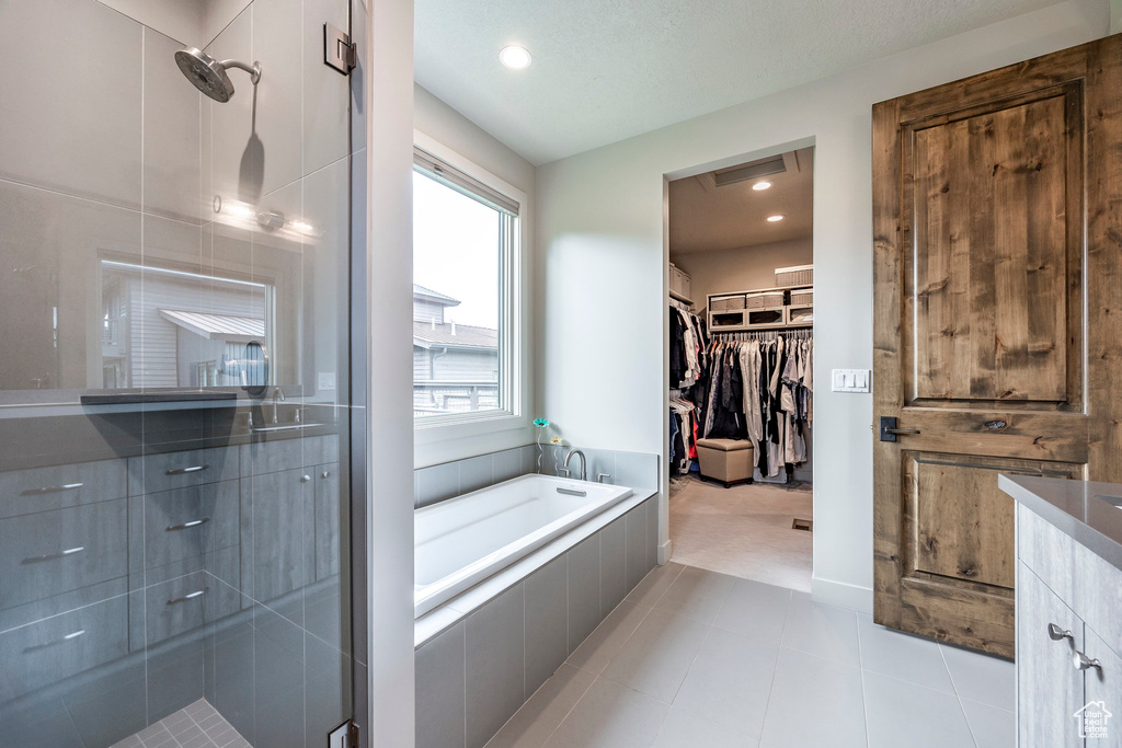 Full bath featuring a garden tub, a shower stall, a walk in closet, tile patterned floors, and recessed lighting