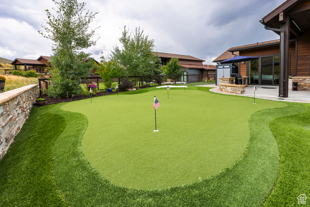 View of property's community featuring a fenced backyard, a putting green, and a patio