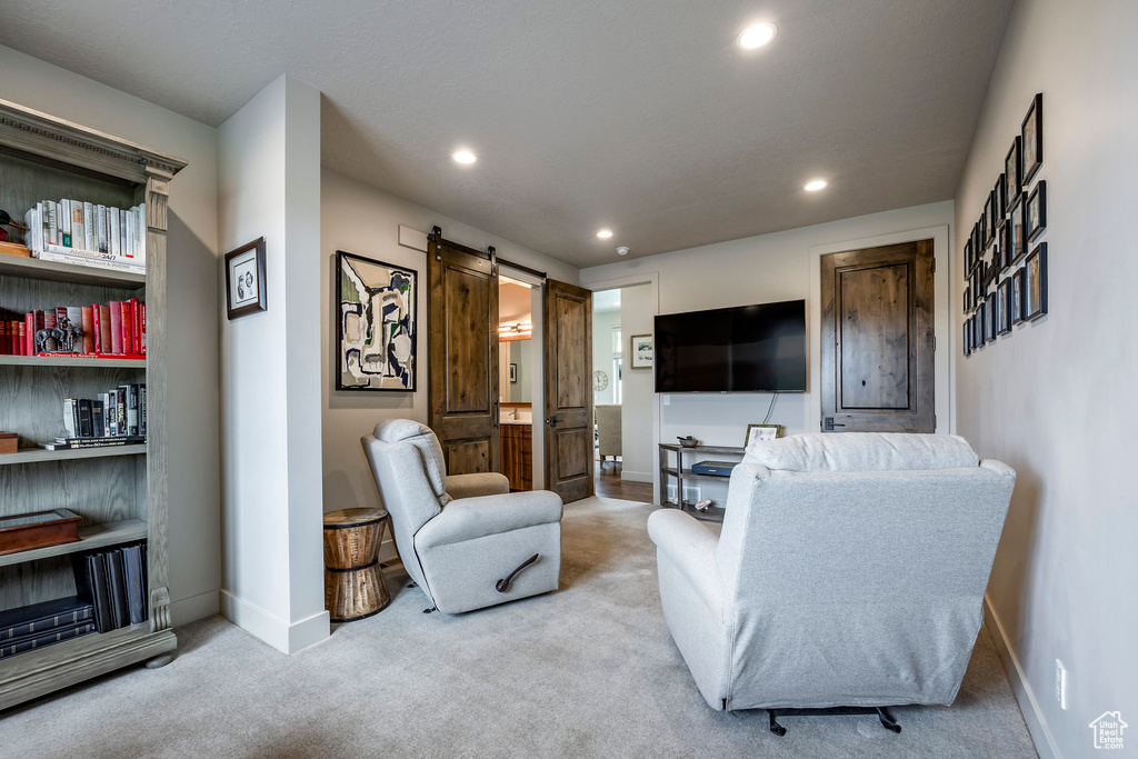 Living room featuring carpet floors, baseboards, recessed lighting, and a barn door