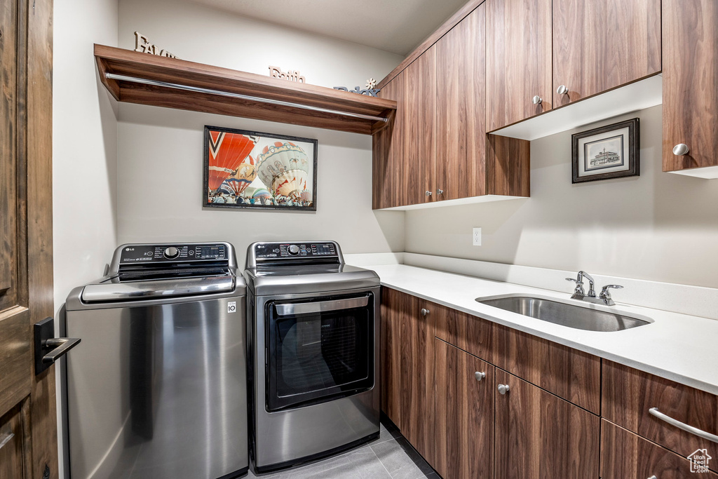 Laundry area with cabinet space, separate washer and dryer, and light tile patterned flooring