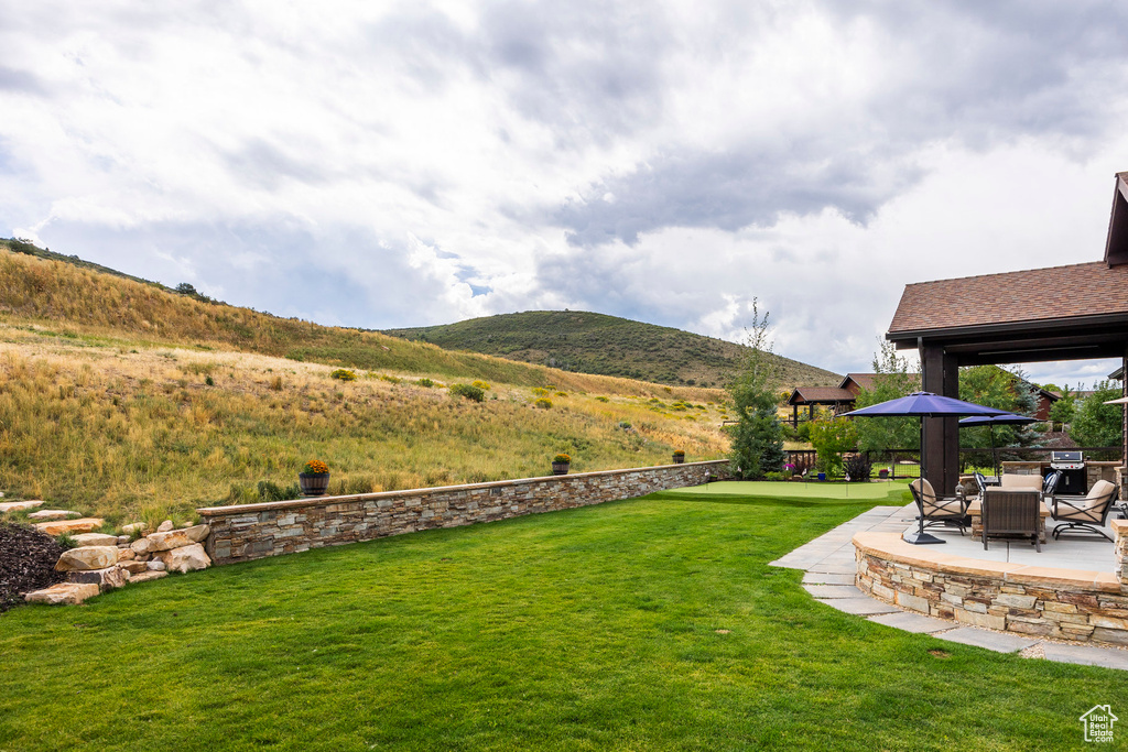 View of green lawn with a patio and a mountain view