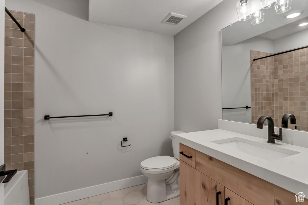 Full bathroom with tile patterned flooring, vanity, toilet, and tiled shower / bath combo