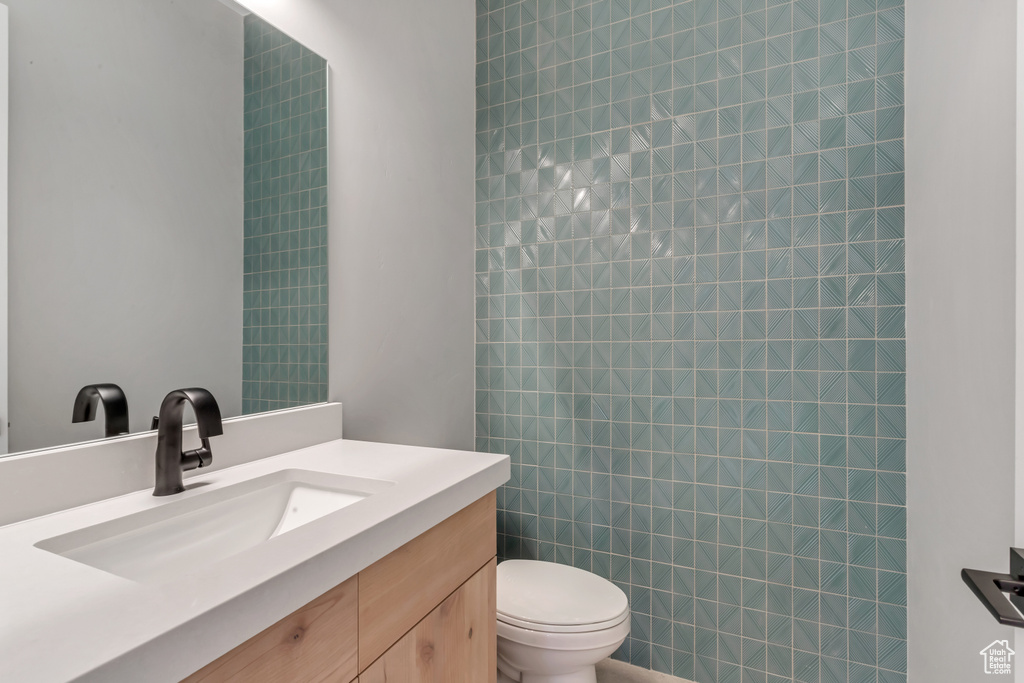 Bathroom featuring vanity, toilet, and tile walls