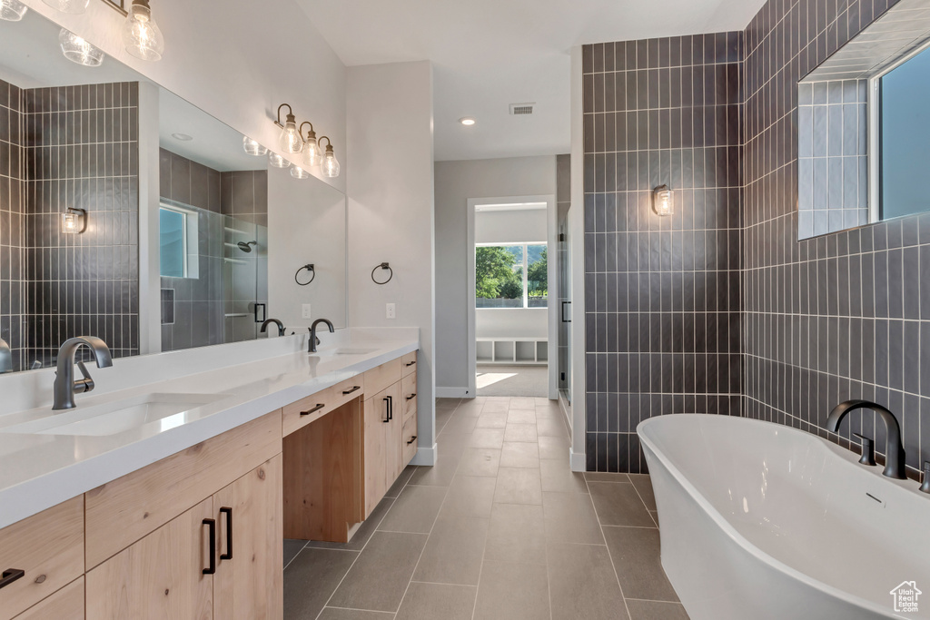 Bathroom with tile patterned floors, vanity, tile walls, and shower with separate bathtub