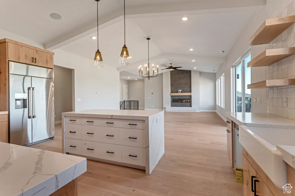 Kitchen featuring a center island, light hardwood / wood-style flooring, a large fireplace, built in refrigerator, and tasteful backsplash