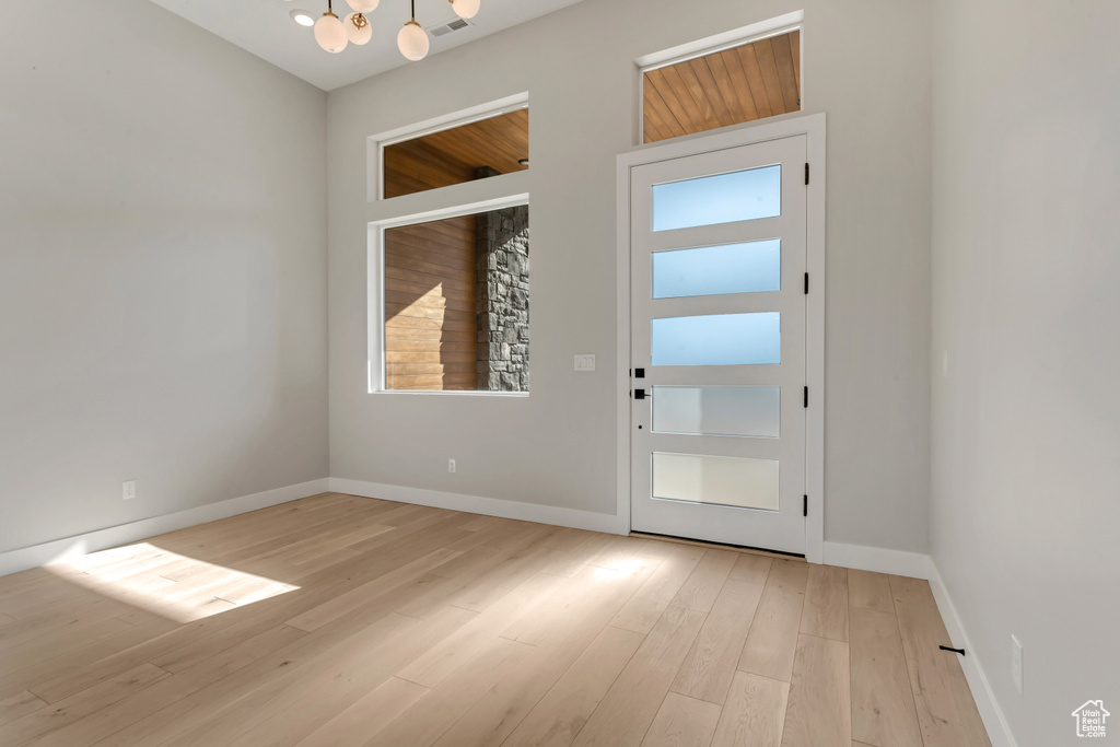 Doorway featuring an inviting chandelier and light hardwood / wood-style flooring