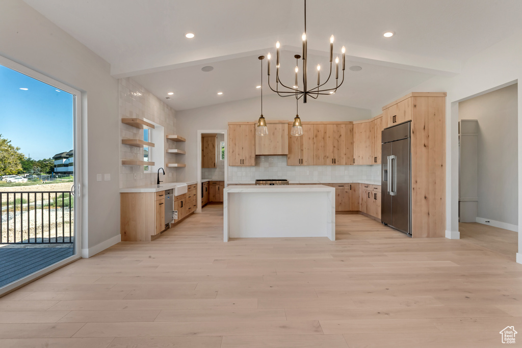 Kitchen featuring a kitchen island, vaulted ceiling, backsplash, appliances with stainless steel finishes, and light hardwood / wood-style floors