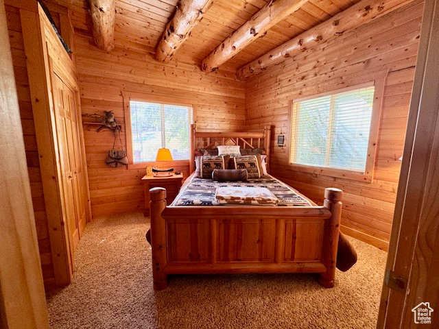 Bedroom with multiple windows, wooden walls, and beam ceiling