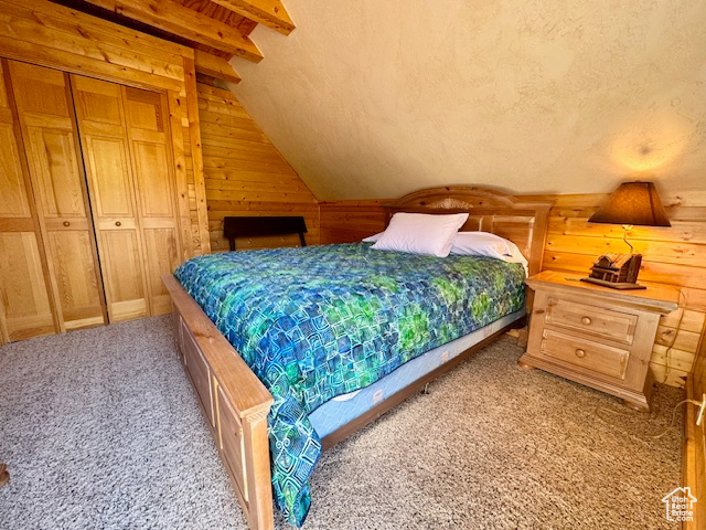 Bedroom with a closet, carpet floors, lofted ceiling with beams, and a textured ceiling