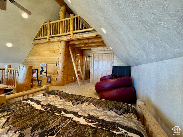 Bedroom with a textured ceiling, vaulted ceiling, and wood walls