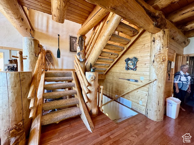 Stairs featuring wood-type flooring, beam ceiling, and wooden ceiling