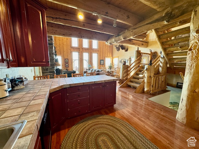 Kitchen featuring tile countertops, hardwood / wood-style floors, beam ceiling, and sink