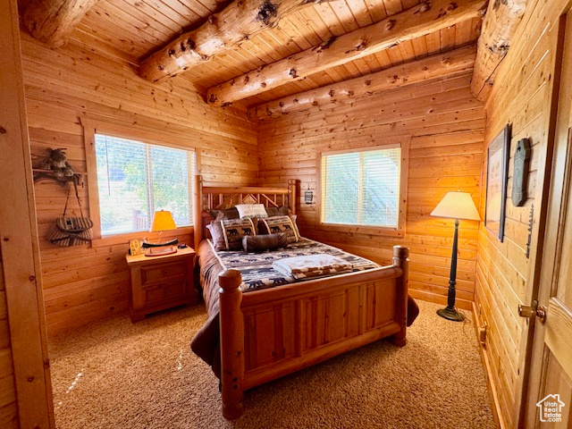 Carpeted bedroom with wooden ceiling, beam ceiling, and wooden walls