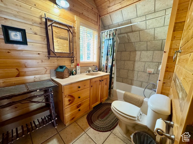 Full bathroom with tile patterned flooring, wooden walls, toilet, shower / tub combo with curtain, and vanity