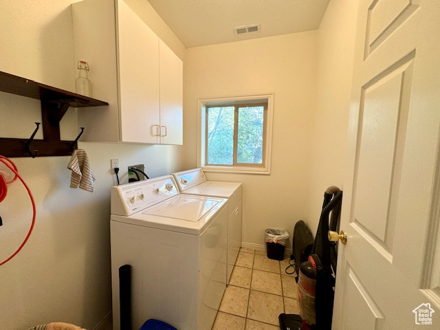 Washroom with cabinets, washing machine and dryer, and light tile patterned flooring