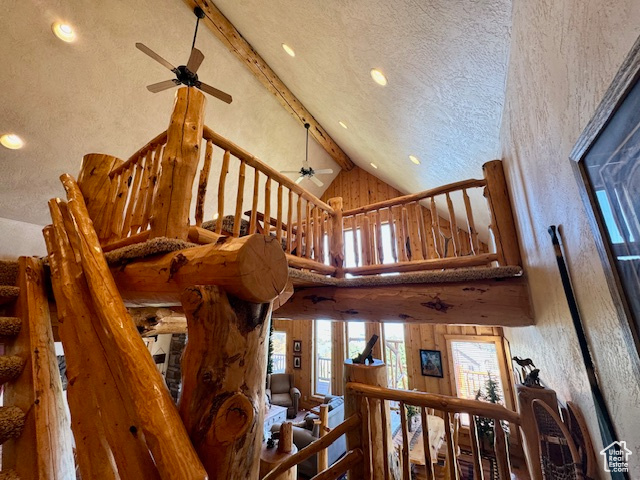 Stairway with high vaulted ceiling, ceiling fan, beamed ceiling, and a textured ceiling