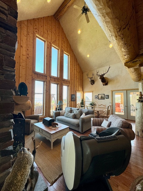 Living room featuring high vaulted ceiling, wood-type flooring, beam ceiling, and ceiling fan