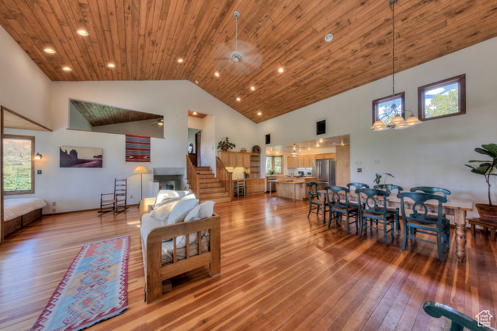 Living room featuring high vaulted ceiling, light wood finished floors, stairway, healthy amount of natural light, and wooden ceiling