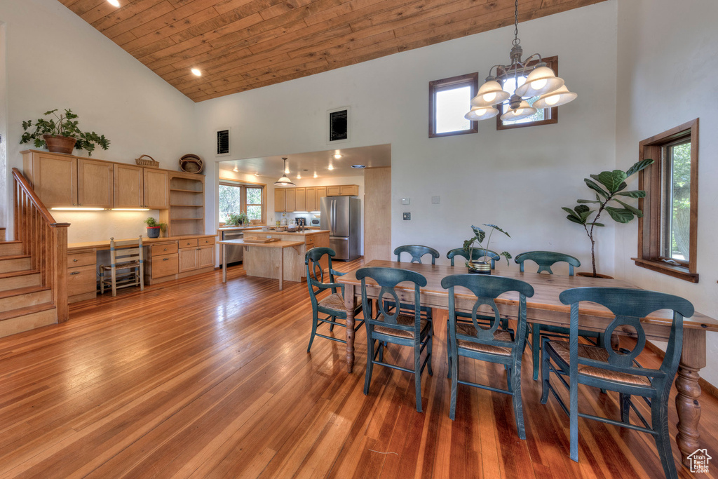 Dining space featuring high vaulted ceiling, light wood-style floors, wooden ceiling, a chandelier, and stairs