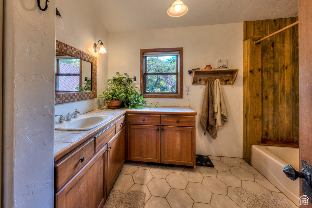 Bathroom with plenty of natural light, vanity, tile patterned floors, and a tub to relax in