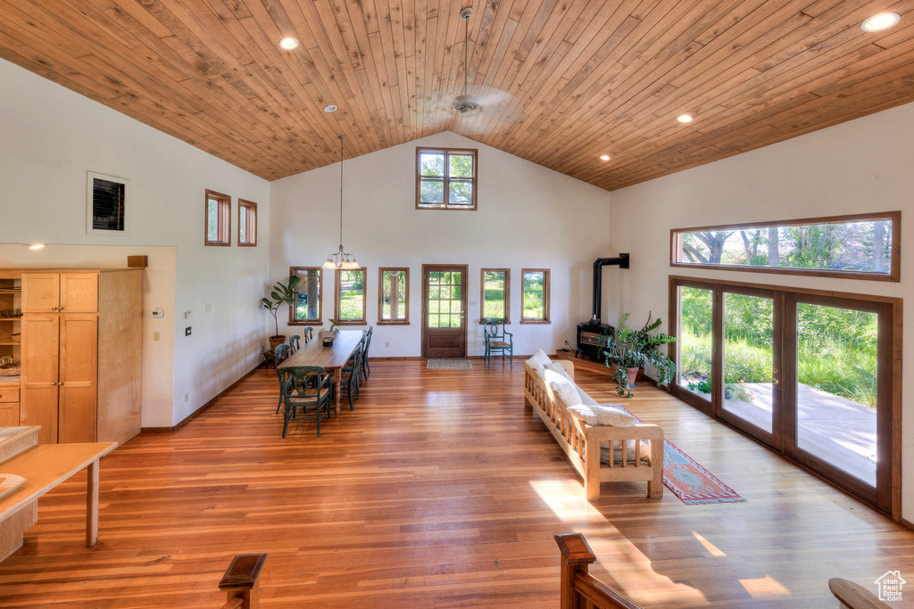 Living area with a wood stove, high vaulted ceiling, wooden ceiling, light wood-style flooring, and recessed lighting