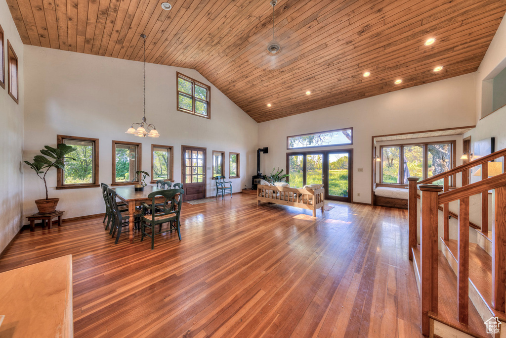 Dining area with high vaulted ceiling, hardwood / wood-style floors, a chandelier, wooden ceiling, and stairs