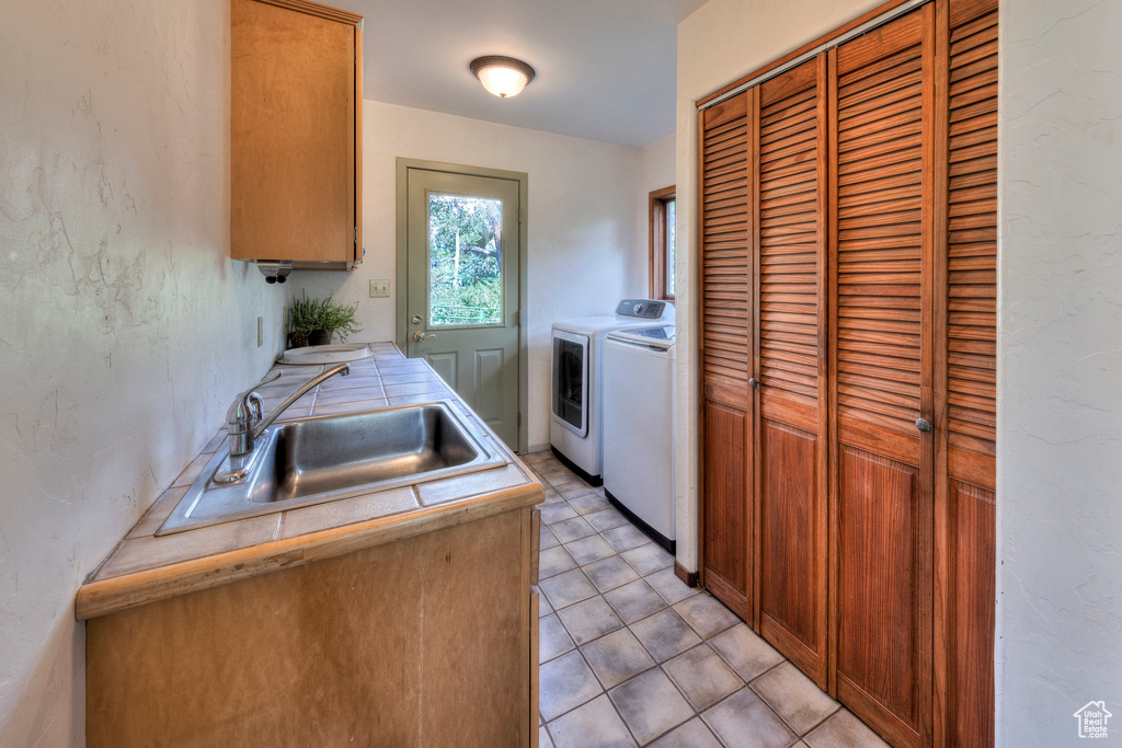 Kitchen featuring a sink, independent washer and dryer, tile countertops, and brown cabinets