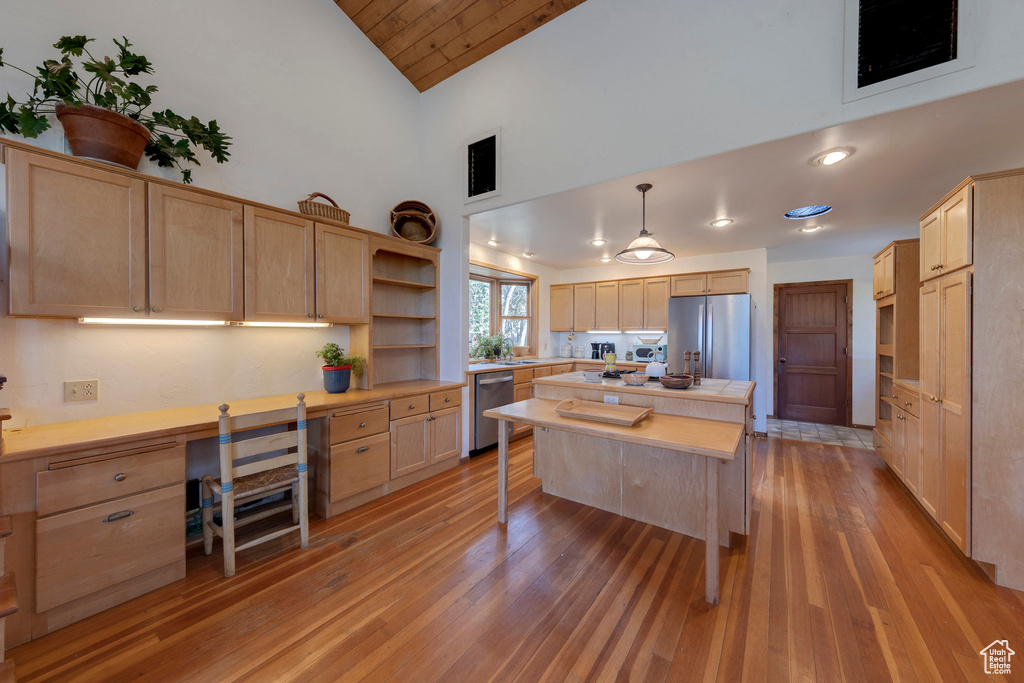 Kitchen featuring stainless steel appliances, light brown cabinetry, high vaulted ceiling, light wood-style flooring, and open shelves