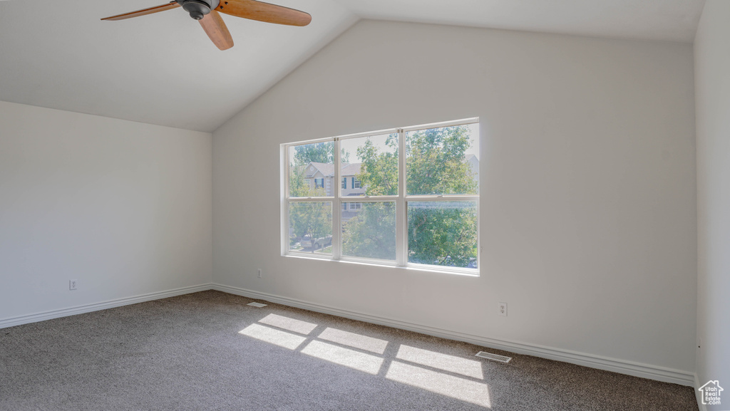 Empty room featuring lofted ceiling, ceiling fan, and carpet flooring