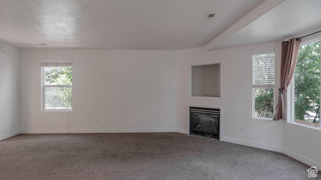 Unfurnished living room featuring a healthy amount of sunlight and carpet floors