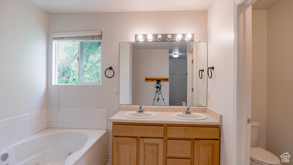 Bathroom featuring toilet, tiled bath, and vanity