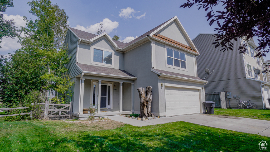 View of front of home with a garage, a porch, and a front lawn