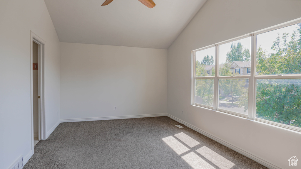 Carpeted empty room featuring lofted ceiling and ceiling fan