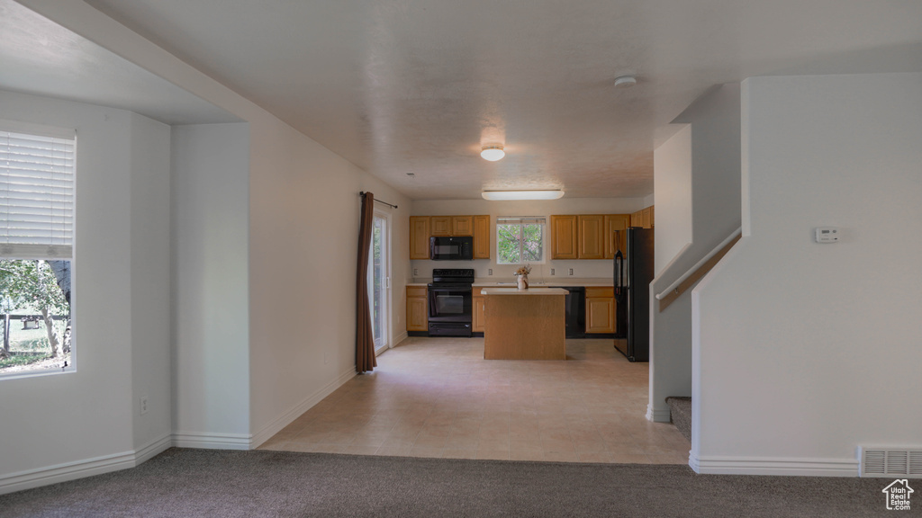 Kitchen with black appliances, plenty of natural light, and a center island