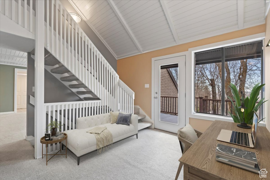 Living area featuring vaulted ceiling with beams, carpet floors, and stairway