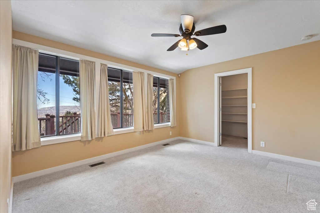 Spare room featuring carpet floors, baseboards, visible vents, and ceiling fan