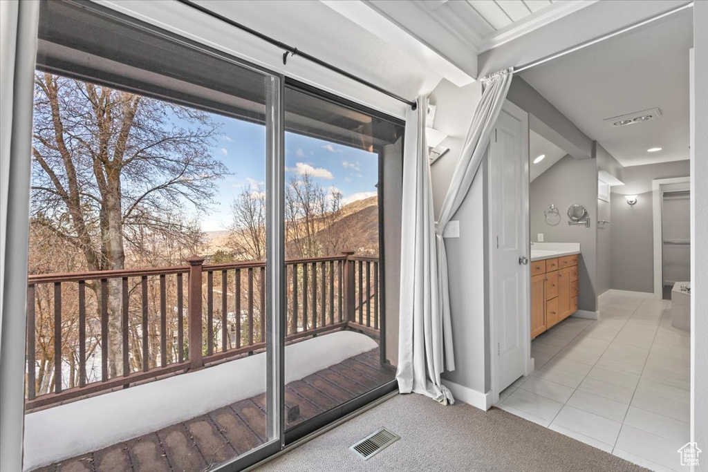 Doorway to outside featuring light carpet, light tile patterned floors, baseboards, and visible vents