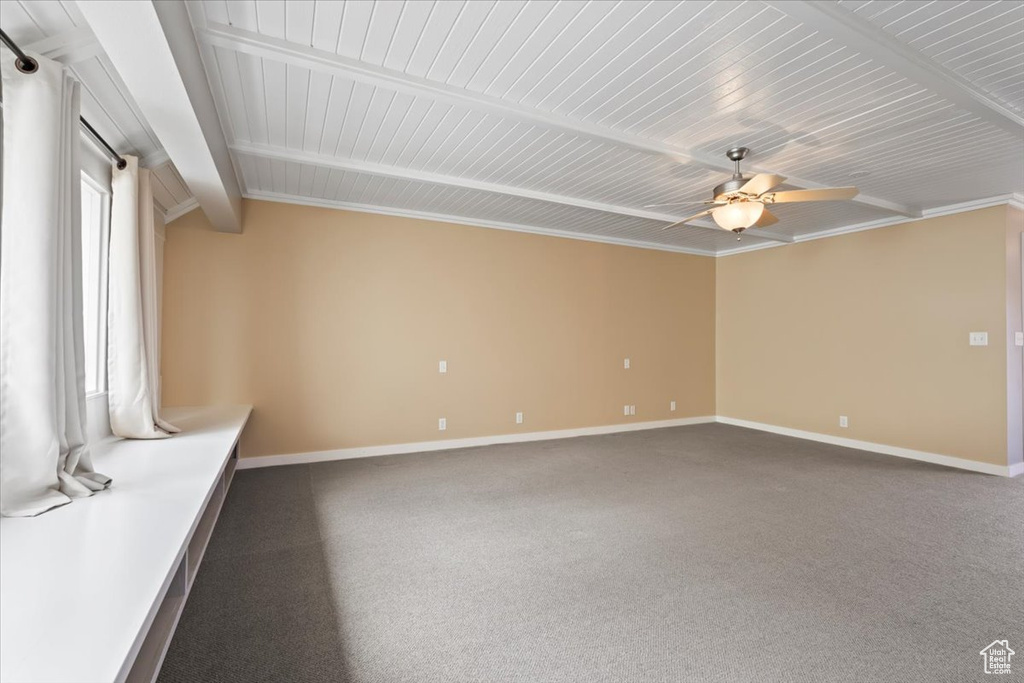 Spare room with beamed ceiling, carpet flooring, a ceiling fan, and baseboards